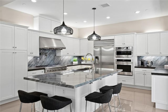 131 Spiral, Irvine, CA 92618 - kitchen featuring stainless steel appliances, exhaust hood, decorative backsplash, a kitchen breakfast bar, and recessed lighting