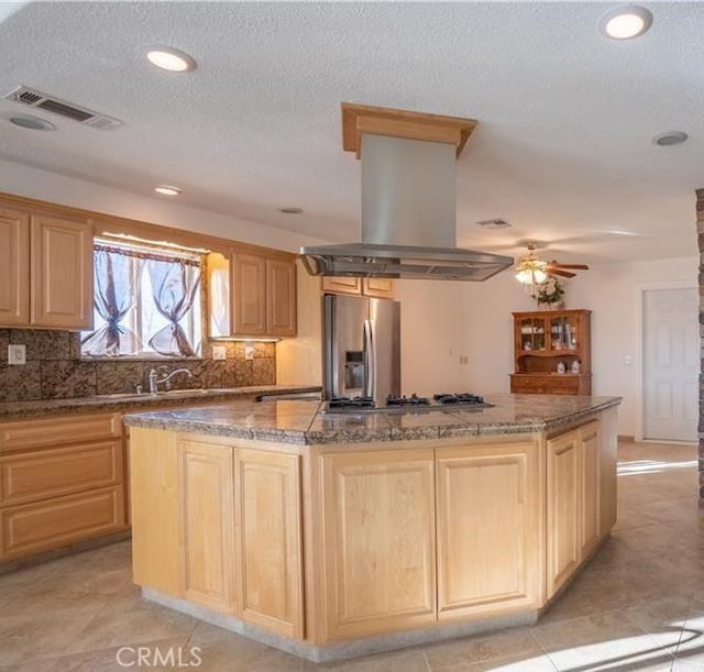 61975 La Brisa Dr, Joshua Tree, CA 92252 - kitchen featuring appliances with stainless steel finishes, island exhaust hood, a center island, light brown cabinets, and backsplash