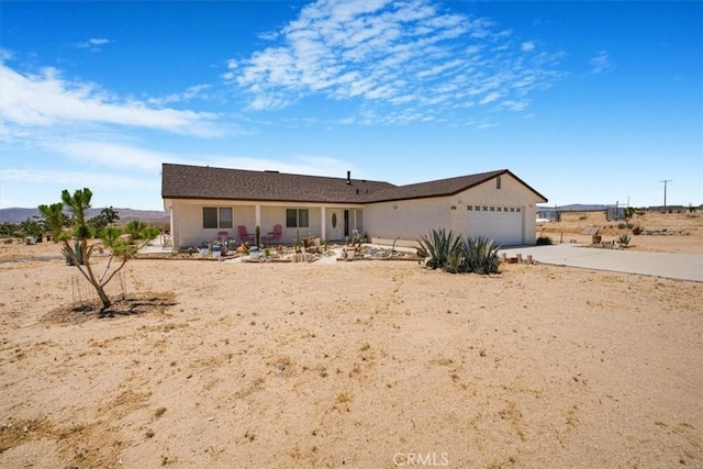 61975 La Brisa Dr, Joshua Tree, CA 92252 - ranch-style house featuring driveway, a garage, stucco siding, and a porch