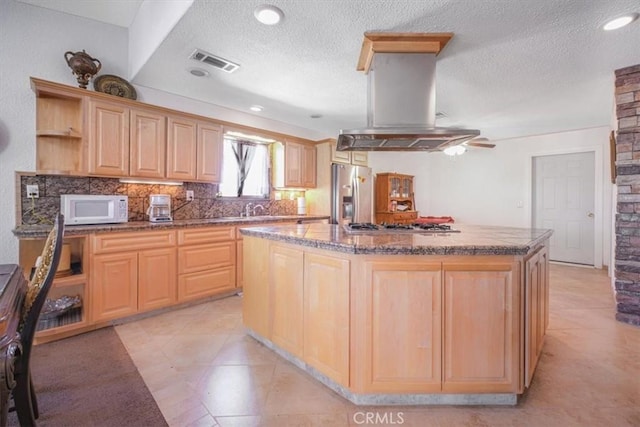 61975 La Brisa Dr, Joshua Tree, CA 92252 - kitchen with white microwave, stainless steel fridge, light brown cabinets, island exhaust hood, and a textured ceiling