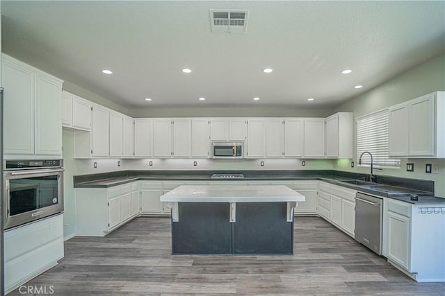 11935 Silver, Jurupa Valley, CA 91752 - kitchen with appliances with stainless steel finishes, recessed lighting, white cabinets, a kitchen island, and wood finished floors