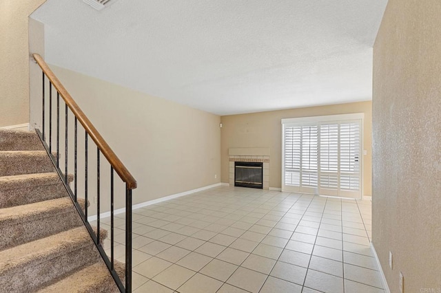 8041 Lomand Ct, Sacramento, CA 95828 - unfurnished living room with light tile patterned floors, a tiled fireplace, stairway, and a textured wall