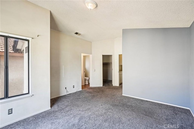 1497 Ruby Dr, Perris, CA 92571 - unfurnished bedroom with dark colored carpet, a textured ceiling, a walk in closet, and a closet