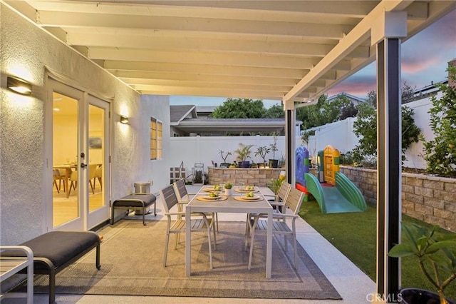 22832 Larkin St, Lake Forest, CA 92630 - patio terrace at dusk featuring outdoor dining space, a fenced backyard, french doors, a patio, and a playground