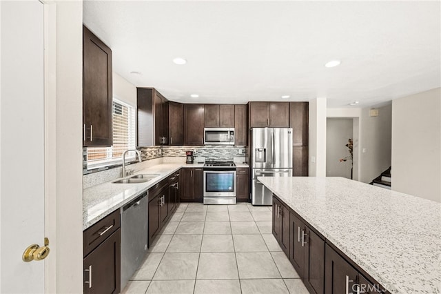 25969 Magnifica Ct, Moreno Valley, CA 92551 - kitchen featuring stainless steel appliances, dark brown cabinetry, tasteful backsplash, light stone counters, and light tile patterned floors
