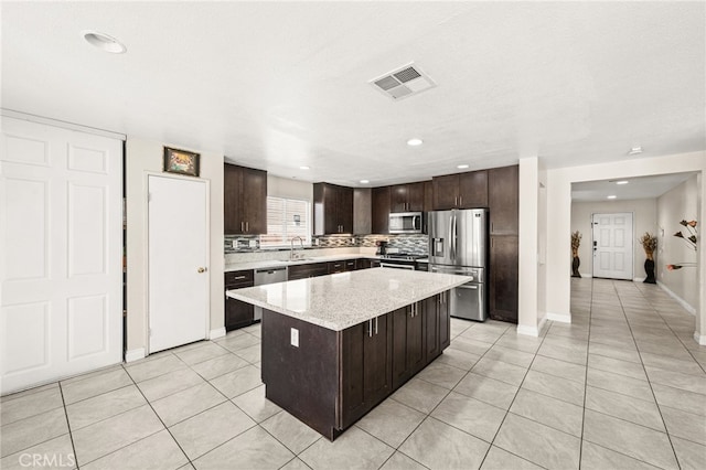 25969 Magnifica Ct, Moreno Valley, CA 92551 - kitchen with stainless steel appliances, dark brown cabinets, light tile patterned floors, a center island, and recessed lighting