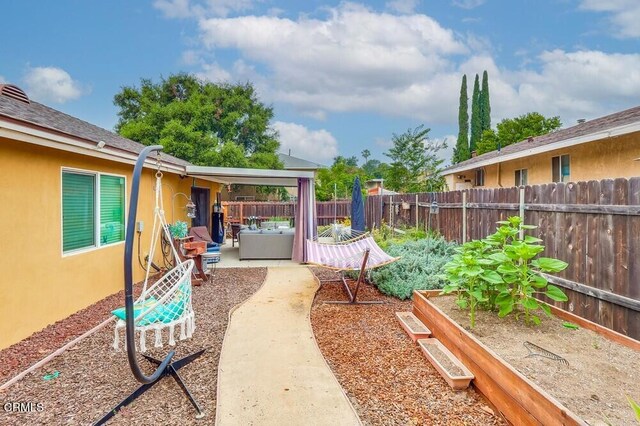  - fenced yard featuring a garden and a patio