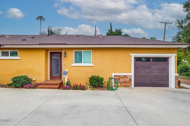  - view of front of property featuring concrete driveway, stucco siding, a garage, and roof with shingles