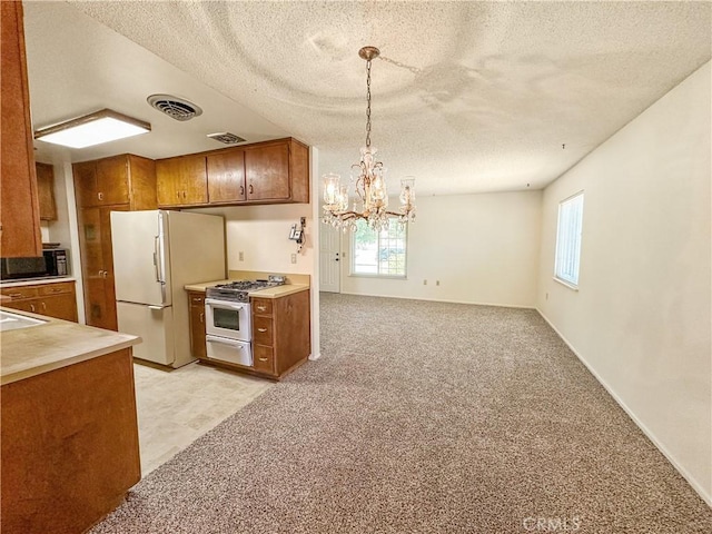 630 N 10 Th St, Blythe, CA 92225 - kitchen featuring high end stove, freestanding refrigerator, brown cabinets, a textured ceiling, and plenty of natural light