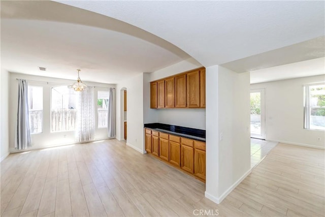 5412 Signac Ct, Chino Hills, CA 91709 - kitchen with light wood-type flooring, brown cabinetry, a chandelier, dark countertops, and arched walkways