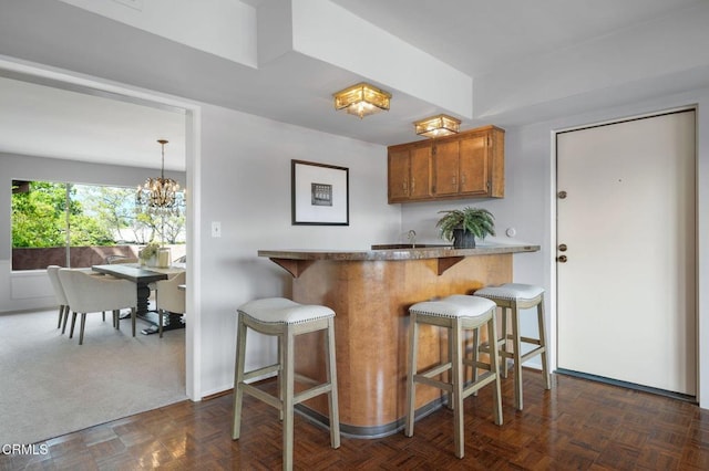 1200 S Orange Grove Blvd Unit 15, Pasadena, CA 91105 - kitchen featuring brown cabinetry, a breakfast bar area, a chandelier, and a peninsula