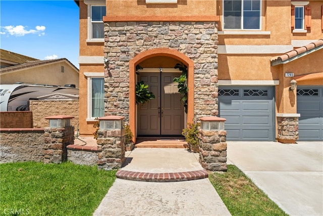 7265 Excelsior Dr, Eastvale, CA 92880 - property entrance with stucco siding, stone siding, a garage, and driveway