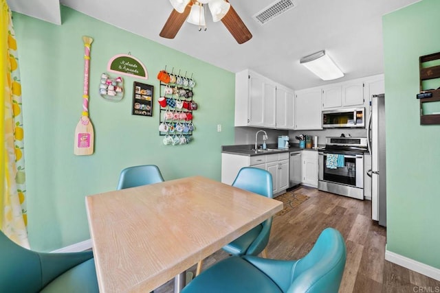 218 Holiday Way, Oceanside, CA 92057 - kitchen featuring appliances with stainless steel finishes, dark wood-type flooring, white cabinetry, ceiling fan, and dark countertops