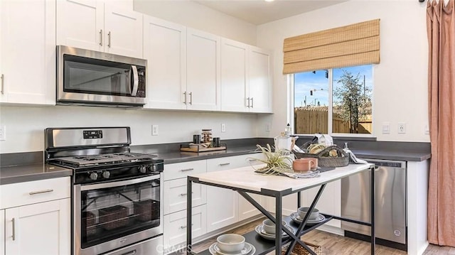 766 Pico Pl, Chico, CA 95928 - kitchen featuring appliances with stainless steel finishes, dark countertops, white cabinetry, and light wood-type flooring