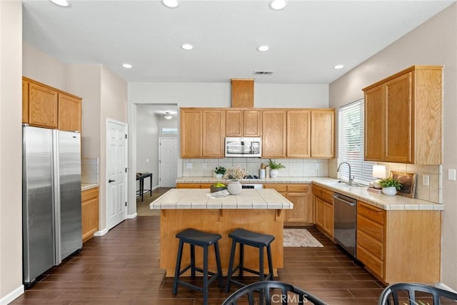 1619 Harvest Glen Dr, Chico, CA 95928 - kitchen with appliances with stainless steel finishes, tile countertops, a kitchen island, dark wood finished floors, and tasteful backsplash