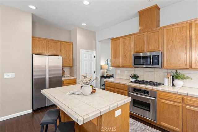 1619 Harvest Glen Dr, Chico, CA 95928 - kitchen with appliances with stainless steel finishes, backsplash, dark wood-type flooring, a kitchen island, and tile countertops