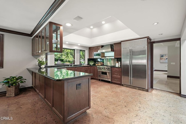 1897 Braemar Rd, Pasadena, CA 91103 - kitchen featuring high end appliances, dark countertops, a peninsula, wall chimney exhaust hood, and glass insert cabinets