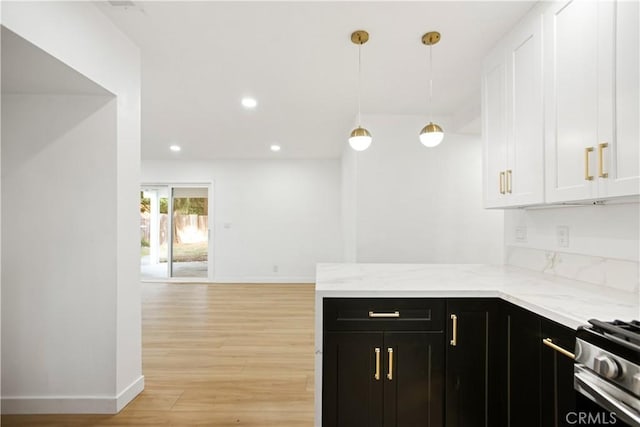 934 W Calora St, San Dimas, CA 91773 - kitchen featuring dark cabinets, white cabinetry, light wood-style floors, light stone countertops, and hanging light fixtures