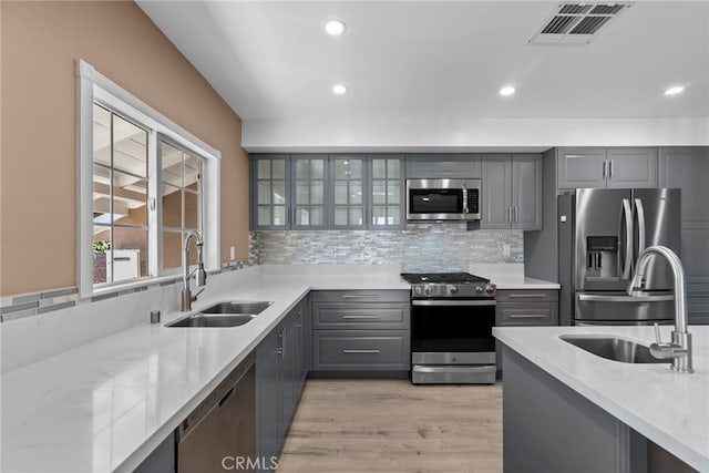15711 Hiawatha St, Granada Hills, CA 91344 - kitchen with appliances with stainless steel finishes, gray cabinetry, backsplash, recessed lighting, and light wood-style flooring