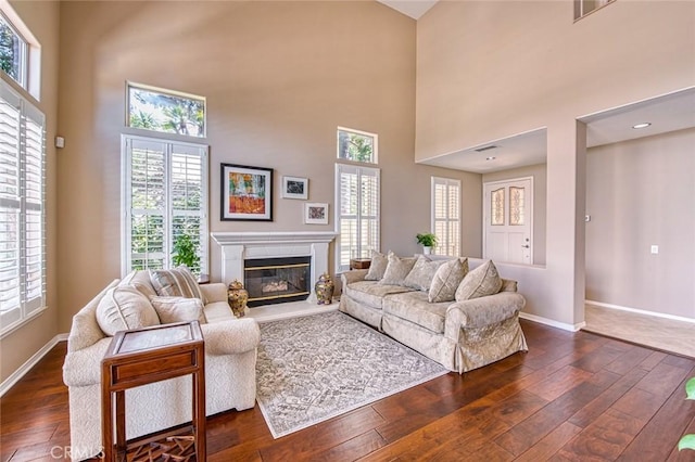 17 Siena, Laguna Niguel, CA 92677 - living room featuring dark wood-type flooring, a glass covered fireplace, healthy amount of natural light, and a towering ceiling