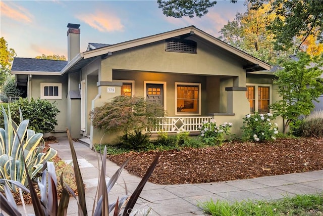 375 E 1st Ave, Chico, CA 95926 - view of front of home featuring covered porch, stucco siding, and a chimney
