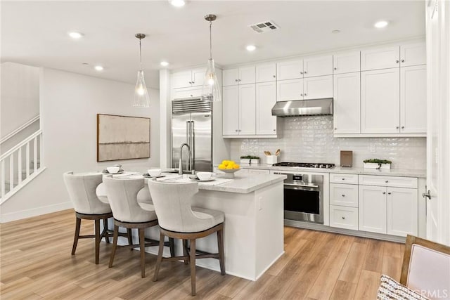 27636 S Evergreen Pl, San Pedro, CA 90732 - kitchen featuring stainless steel appliances, under cabinet range hood, light wood-type flooring, decorative backsplash, and a center island with sink