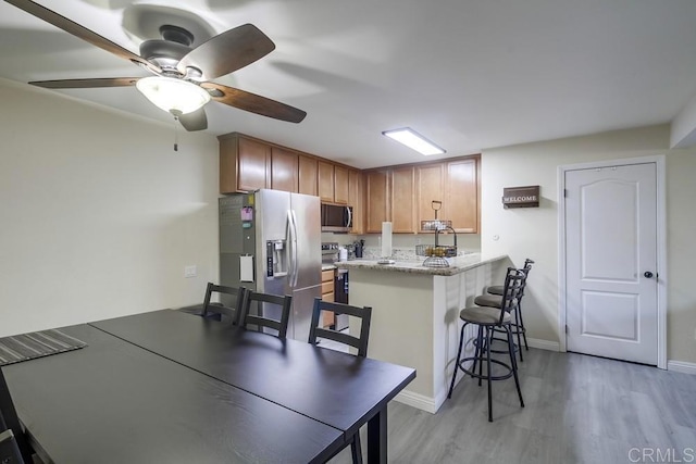 3454 Castle Glen Dr Unit 115, San Diego, CA 92123 - kitchen featuring appliances with stainless steel finishes, light wood finished floors, a peninsula, a breakfast bar, and ceiling fan