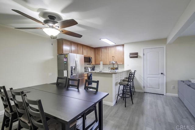 3454 Castle Glen Dr Unit 115, San Diego, CA 92123 - kitchen with stainless steel appliances, a peninsula, light wood-style flooring, a breakfast bar, and ceiling fan