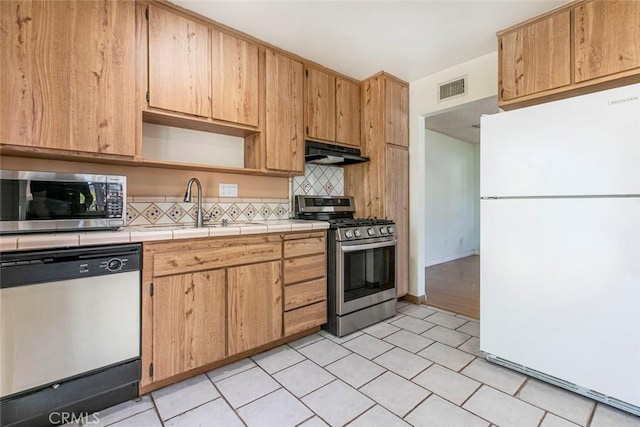 10919 Terecita Rd, Tujunga, CA 91042 - kitchen featuring appliances with stainless steel finishes, under cabinet range hood, tile counters, tasteful backsplash, and open shelves