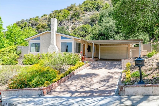 10919 Terecita Rd, Tujunga, CA 91042 - mid-century home with an attached garage, driveway, a chimney, and stucco siding