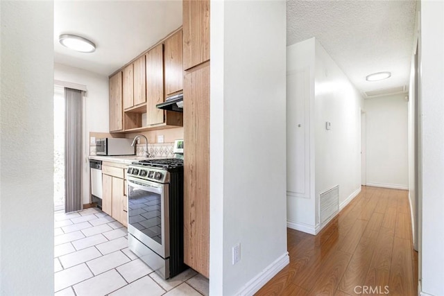 10919 Terecita Rd, Tujunga, CA 91042 - kitchen with stainless steel appliances, light countertops, under cabinet range hood, light wood finished floors, and light brown cabinetry