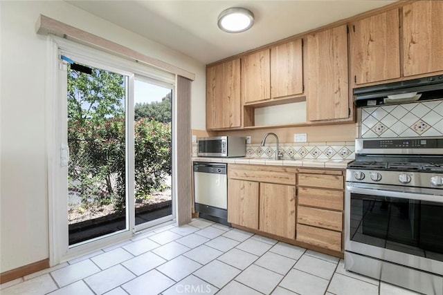 10919 Terecita Rd, Tujunga, CA 91042 - kitchen featuring appliances with stainless steel finishes, under cabinet range hood, tasteful backsplash, and tile counters