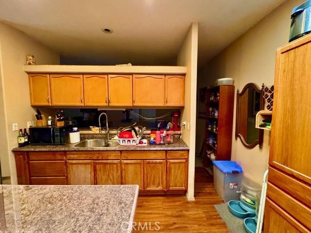 6475 105th St W, Rosamond, CA 93560 - kitchen with wood finished floors, black microwave, and brown cabinets