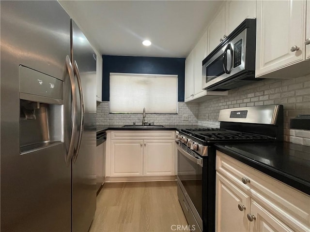 21520 Burbank Blvd Unit 116, Woodland Hills, CA 91367 - kitchen with appliances with stainless steel finishes, dark countertops, light wood finished floors, decorative backsplash, and white cabinetry