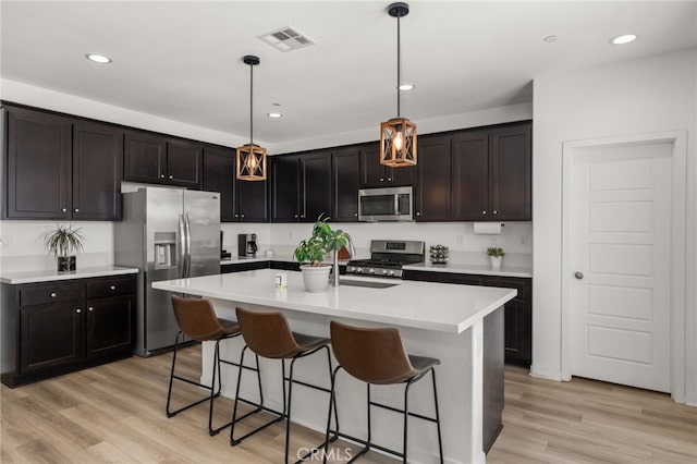 5756 Quicksilver Way, Banning, CA 92220 - kitchen with appliances with stainless steel finishes, a breakfast bar, light wood finished floors, hanging light fixtures, and light countertops