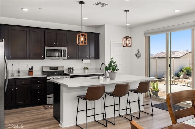 5756 Quicksilver Way, Banning, CA 92220 - kitchen featuring appliances with stainless steel finishes, light wood-type flooring, a kitchen breakfast bar, light countertops, and a kitchen island with sink