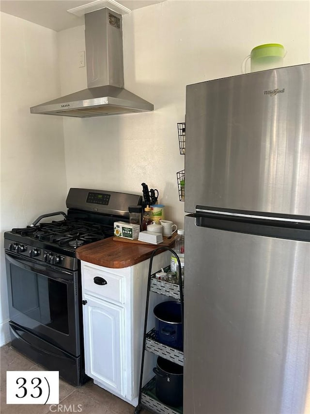 1388 N Lugo Ave, San Bernardino, CA 92404 - kitchen featuring freestanding refrigerator, gas stove, wall chimney range hood, wooden counters, and tile patterned flooring