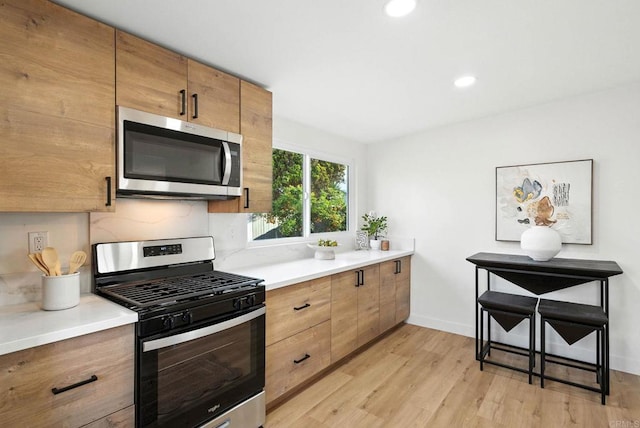 1143 Hemlock Ave, Imperial Beach, CA 91932 - kitchen featuring appliances with stainless steel finishes, light wood-style flooring, light countertops, recessed lighting, and brown cabinetry