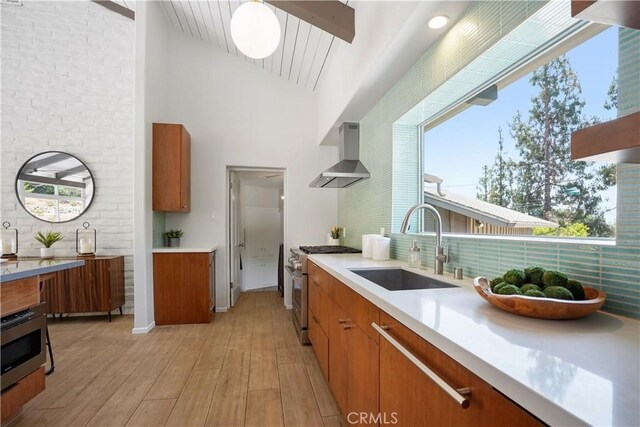 1987 Windover Rd, Pasadena, CA 91107 - kitchen with wall chimney exhaust hood, stainless steel range, brown cabinetry, light wood-style floors, and light countertops