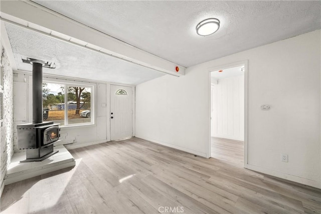44668 Brawley Ave, Jacumba, CA 91934 - unfurnished living room featuring a textured ceiling, wood finished floors, and a wood stove