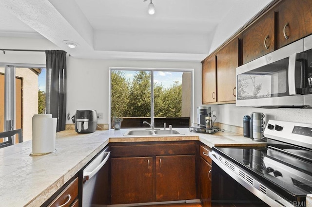 1317 Caminito Gabaldon Unit H, San Diego, CA 92108 - kitchen featuring appliances with stainless steel finishes, plenty of natural light, light countertops, and a raised ceiling