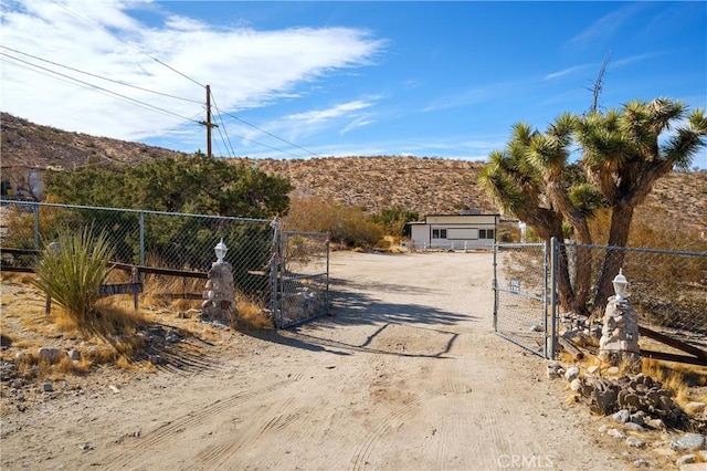 7888 Victor, Yucca Valley, CA 92284 - view of dirt / gravel driveway featuring a gate, a mountain view, and a gated entry