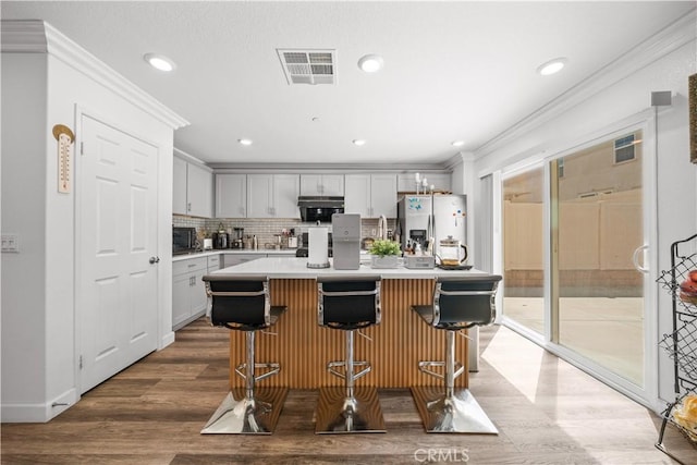 9804 Ardisia St, Riverside, CA 92503 - kitchen with stainless steel fridge, wood finished floors, a kitchen bar, crown molding, and light countertops
