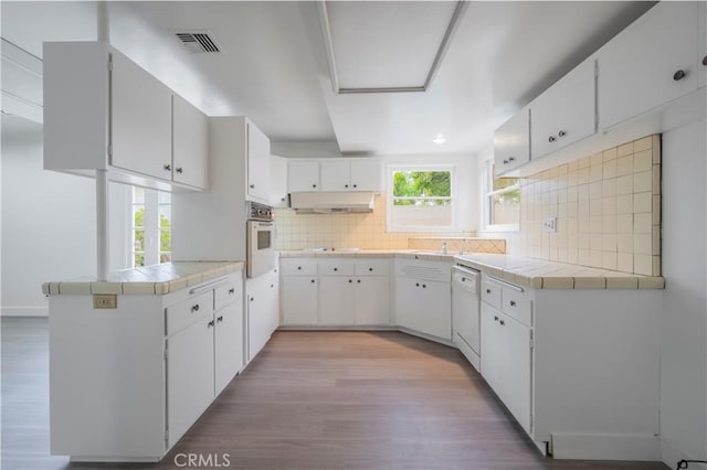 1725 Turnbull Canyon Rd, Hacienda Heights, CA 91745 - kitchen with light wood-style flooring, a peninsula, white dishwasher, backsplash, and tile countertops