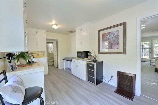 330 N Madison Ave, Monrovia, CA 91016 - kitchen with heating unit, beverage cooler, white cabinetry, light wood-style flooring, and tasteful backsplash