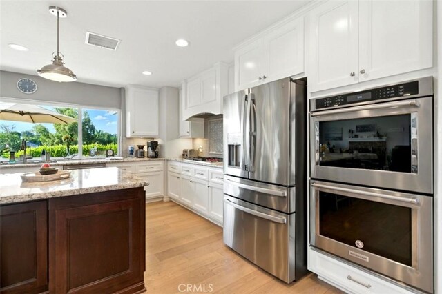 3526 Alder Pl, Chino Hills, CA 91709 - kitchen featuring appliances with stainless steel finishes, white cabinetry, light wood-type flooring, light stone counters, and hanging light fixtures