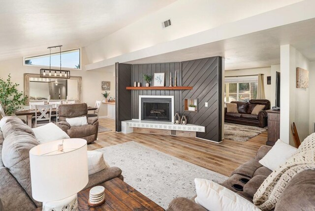 10518 Moon View Way, Escondido, CA 92026 - living area featuring wood finished floors, a fireplace with raised hearth, lofted ceiling, and a chandelier