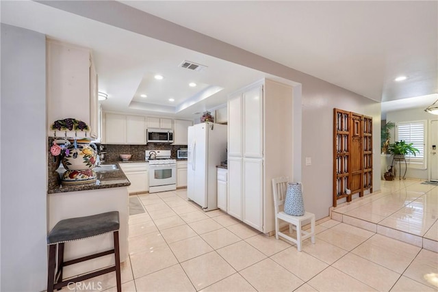 9909 Merced River Ave, Fountain Valley, CA 92708 - kitchen with white appliances, light tile patterned floors, white cabinetry, recessed lighting, and a tray ceiling