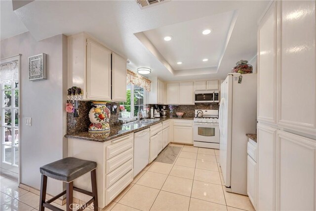 9909 Merced River Ave, Fountain Valley, CA 92708 - kitchen featuring white appliances, tasteful backsplash, recessed lighting, dark stone countertops, and a tray ceiling