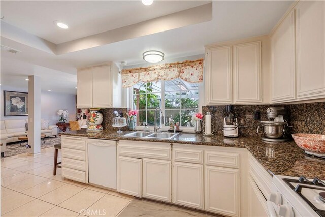 9909 Merced River Ave, Fountain Valley, CA 92708 - kitchen with white appliances, tasteful backsplash, light tile patterned floors, a tray ceiling, and dark stone countertops